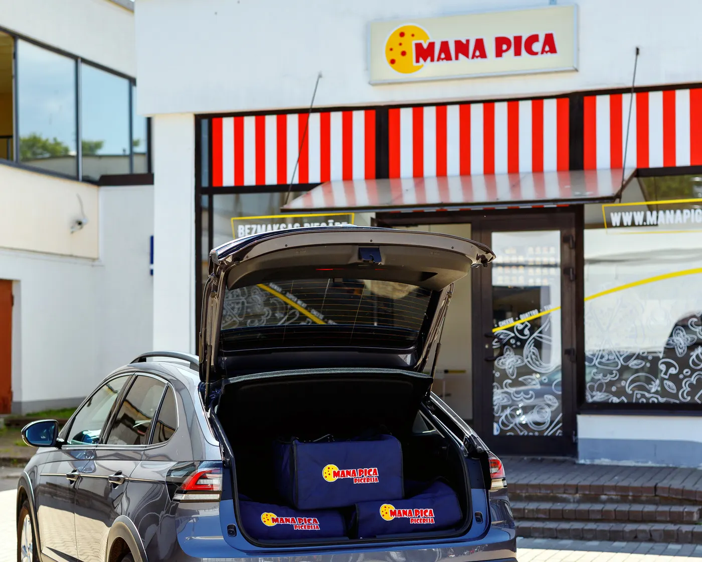 Mana Pica piegādes somas mašīnas bagāžniekā pie picērijas